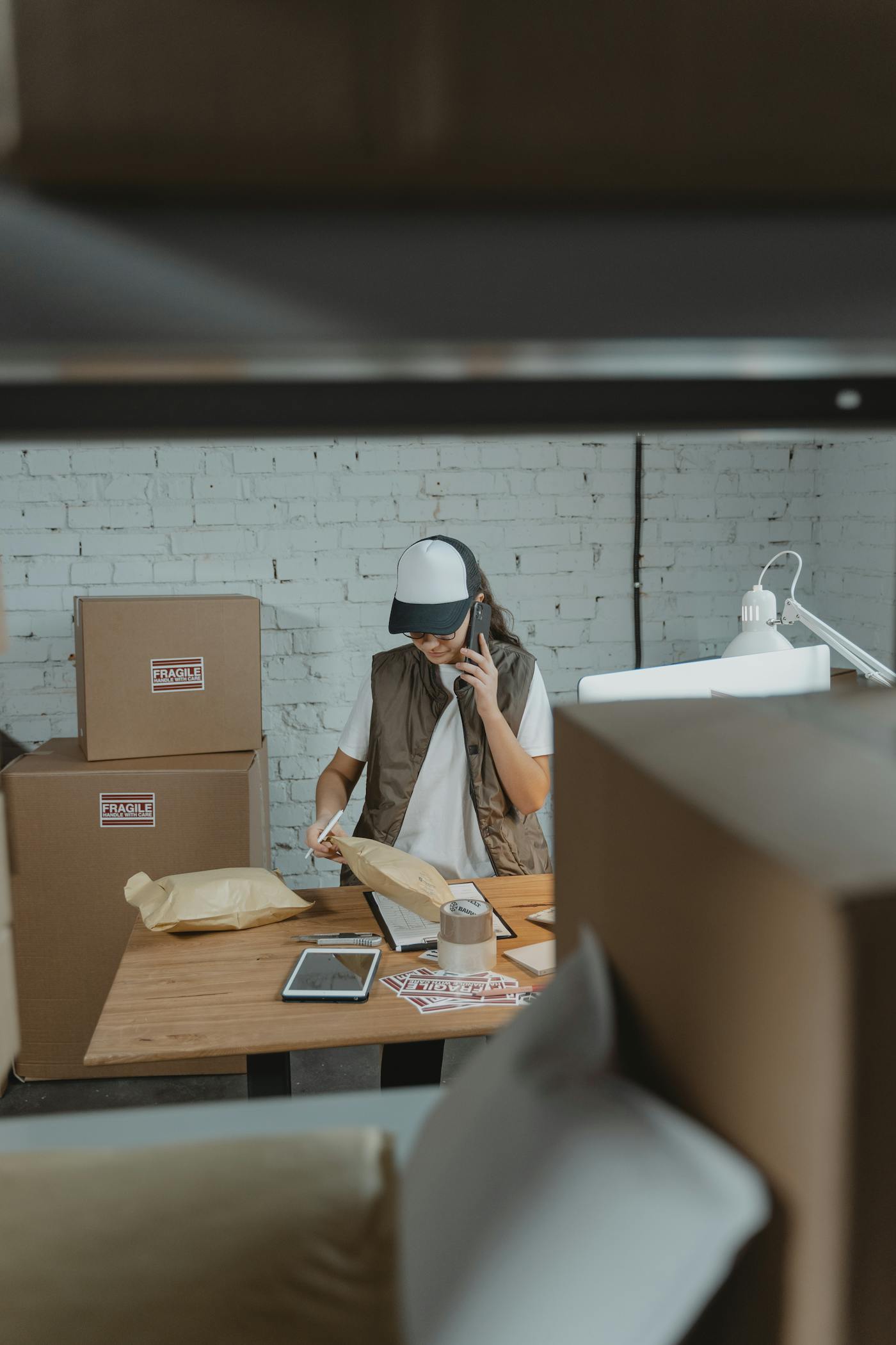 Logistics staff on a phone call while preparing parcels for delivery.